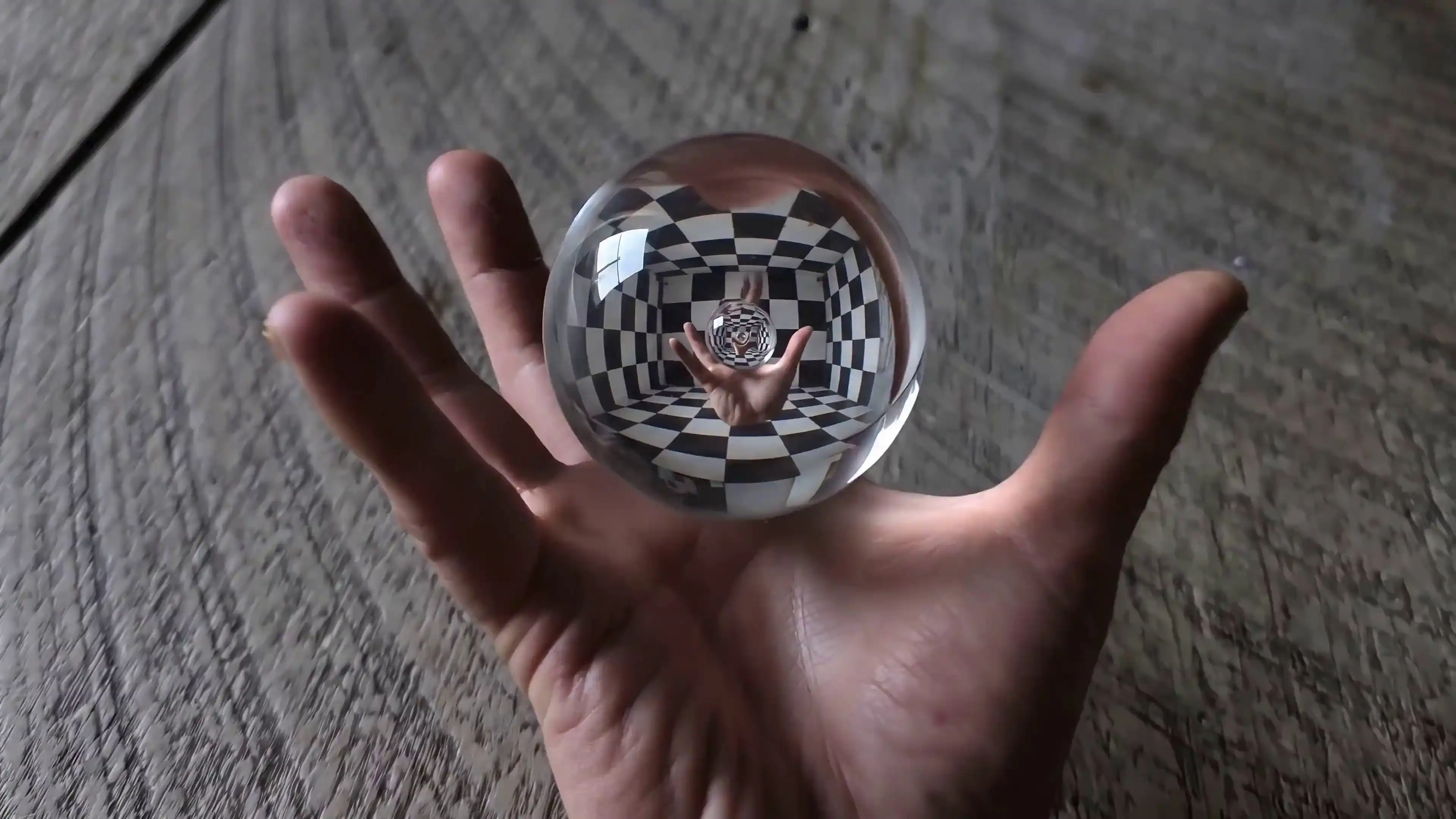 Glass sphere containing an infinite recursive checkerboard room floating above a hand, created with Gemini Omni Flash