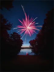 Gemini Omni - Mirrored dual firework explosion over a calm lake with crystalline particle bursts.